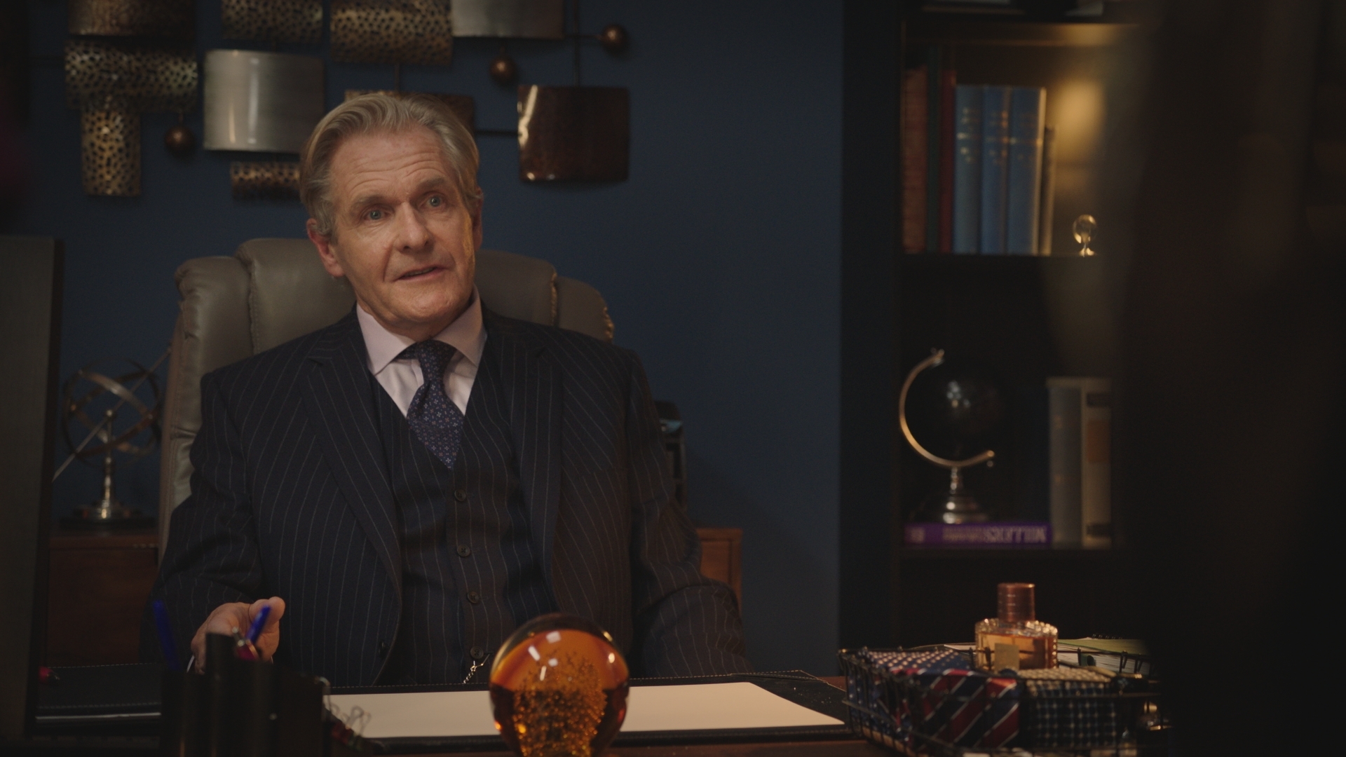 Russell Whitelaw in a pinstripe suit in his plush office.