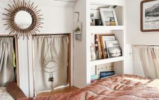 Tidy bedroom space in van with white shelving and dusty pink throw over the edge of the bed