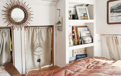 Tidy bedroom space in van with white shelving and dusty pink throw over the edge of the bed