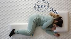 A woman lies on a Levitex Mattress with a Levitex Sleep Posture Pillow under her head and one between her knees, a cartoon thought bubble with "zzz" is over her head