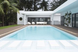 Looking at low modernist Nigerian villa over swimming pool