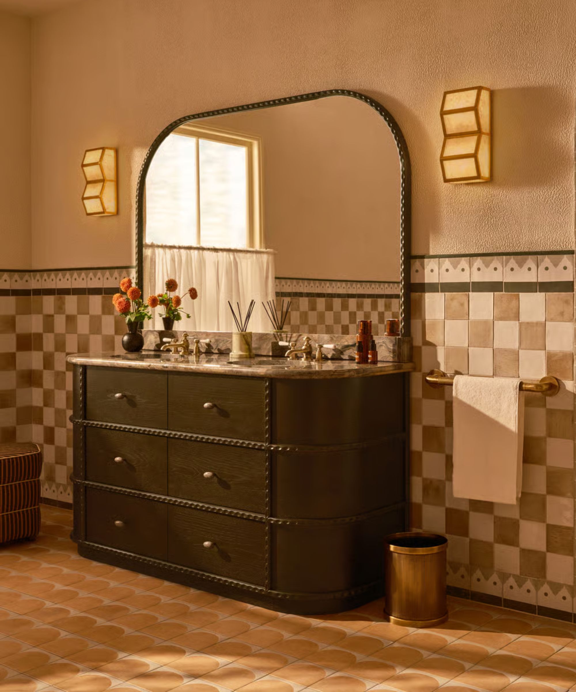 A warm neutral bathroom with white and beige checkerboard wall tiles, a dark wood vanity, and a curved dark wood vanity mirror