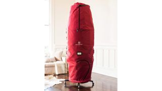 A Christmas tree zipped up in a red rolling Christmas tree storage bag, for the best Christmas tree storage bags.
