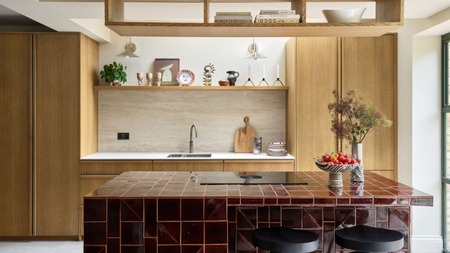a modern kitchen with a red tiled island, wood cabinetry, and kitchen accessories on the countertops