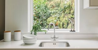 kitchen window behind a sink in a clean white kitchen