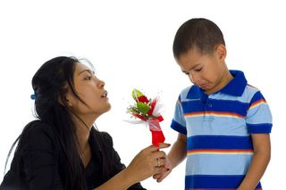 A boy apologizes to his mother with flowers.