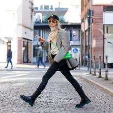 Influencer Saraja Roberta Elez, wearing a grey checked vintage oversize blazer by Oscar de la Renta, a light grey turtleneck by Saraja Roberta Elez, black leggings by Saraja Roberta Elez, a green mini bag by Balenciaga, a black cap with Marant print by Isabel Marant, black boots with green sole by Bottega Veneta and sunglasses by Bottega Veneta, during a streetstyle shooting on October 11, 2021 in Frankfurt am Main, Germany.