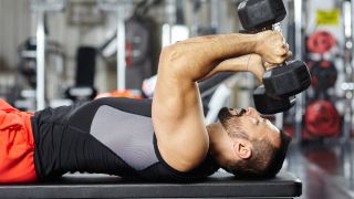Man performs dumbbell skullcrusher in gym
