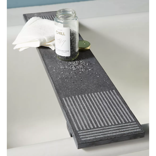 charcoal slate bath caddy with lined grooves and bath accessories on top