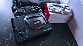 A retro gaming console with "16-BIT" written on it is placed on a surface next to an open box revealing a modern circuit board, creating a contrast between old and new technology.