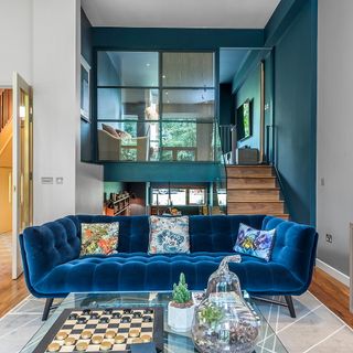 living room with brown wooden stairs and blue sofa set