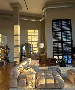 A neutral living room with a couch, table, and black blinds