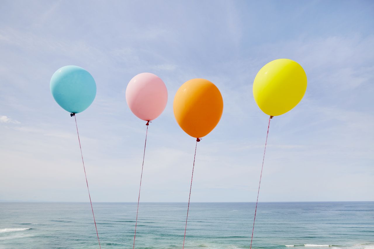 image of four balloons near a body of water