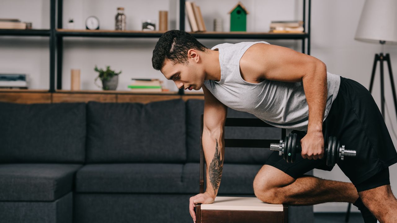 Full-body dumbbell workout: a man doing a dumbbell row at home