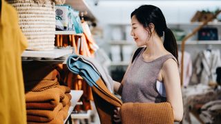 Woman holding up sofa throw in the shop to look at closely