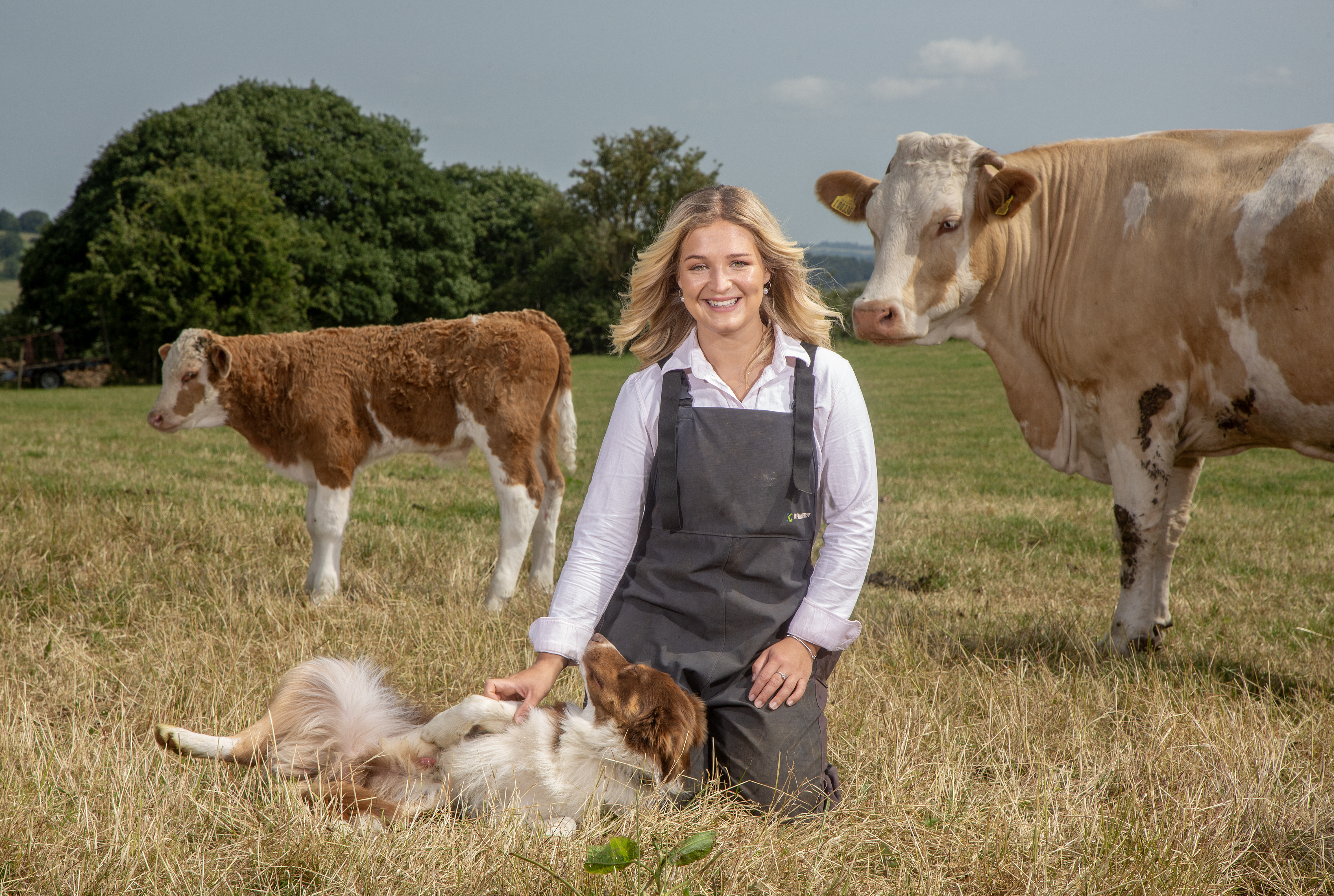 Harriet Cowan posing in dungarees for the Country Life Frontispiece with a dog and two cows