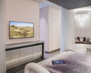Bedroom TV mounted onto wall with sheer panels to hide it when not in use