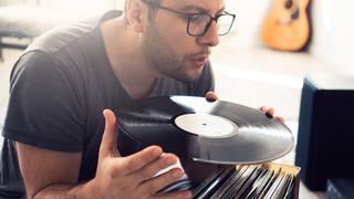 Best vinyl record cleaners: Man blowing across a vinyl record