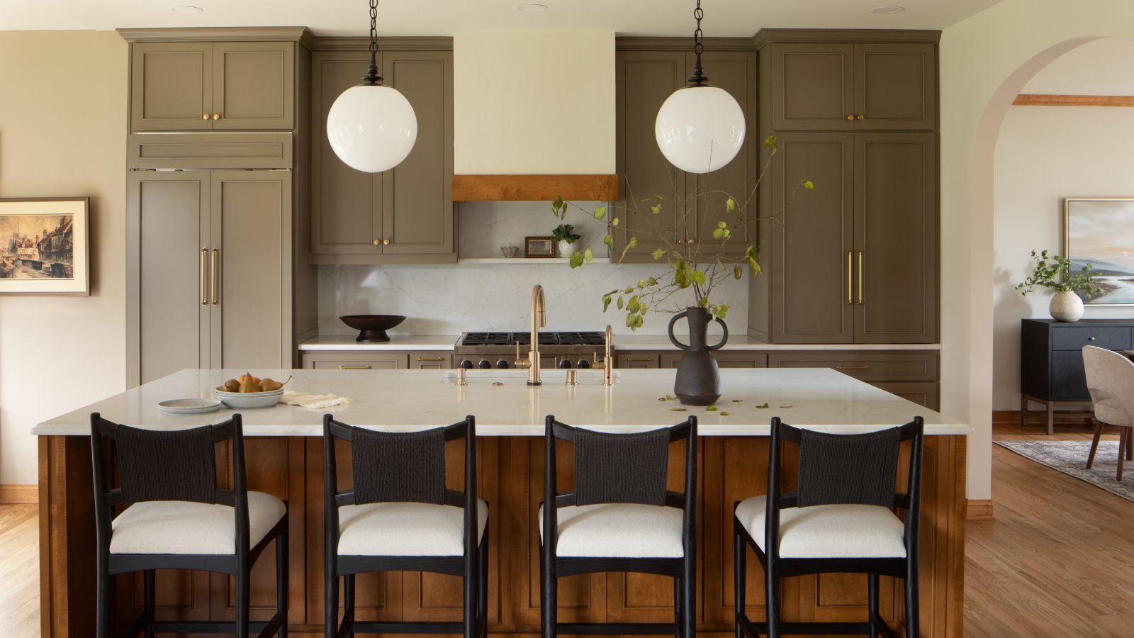 A large kitchen with muddy green cabinets and a wooden island