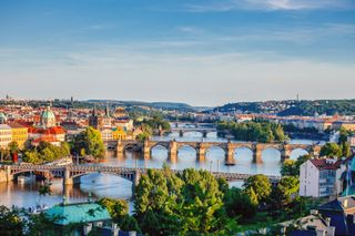 Panoramic view of Prague's Old Town, Vlata River and famous bridges at sunset.