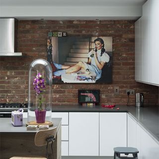 kitchen room with exposed brick wall and white cabinets