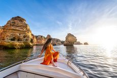 Woman sailing on the yacht near the rocky coast of Algarve, Portugal