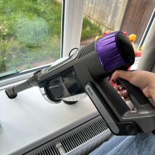 Shark PowerDetect Clean and Empty Cordless Vacuum being used in handheld mode with crevice tool on windowsill