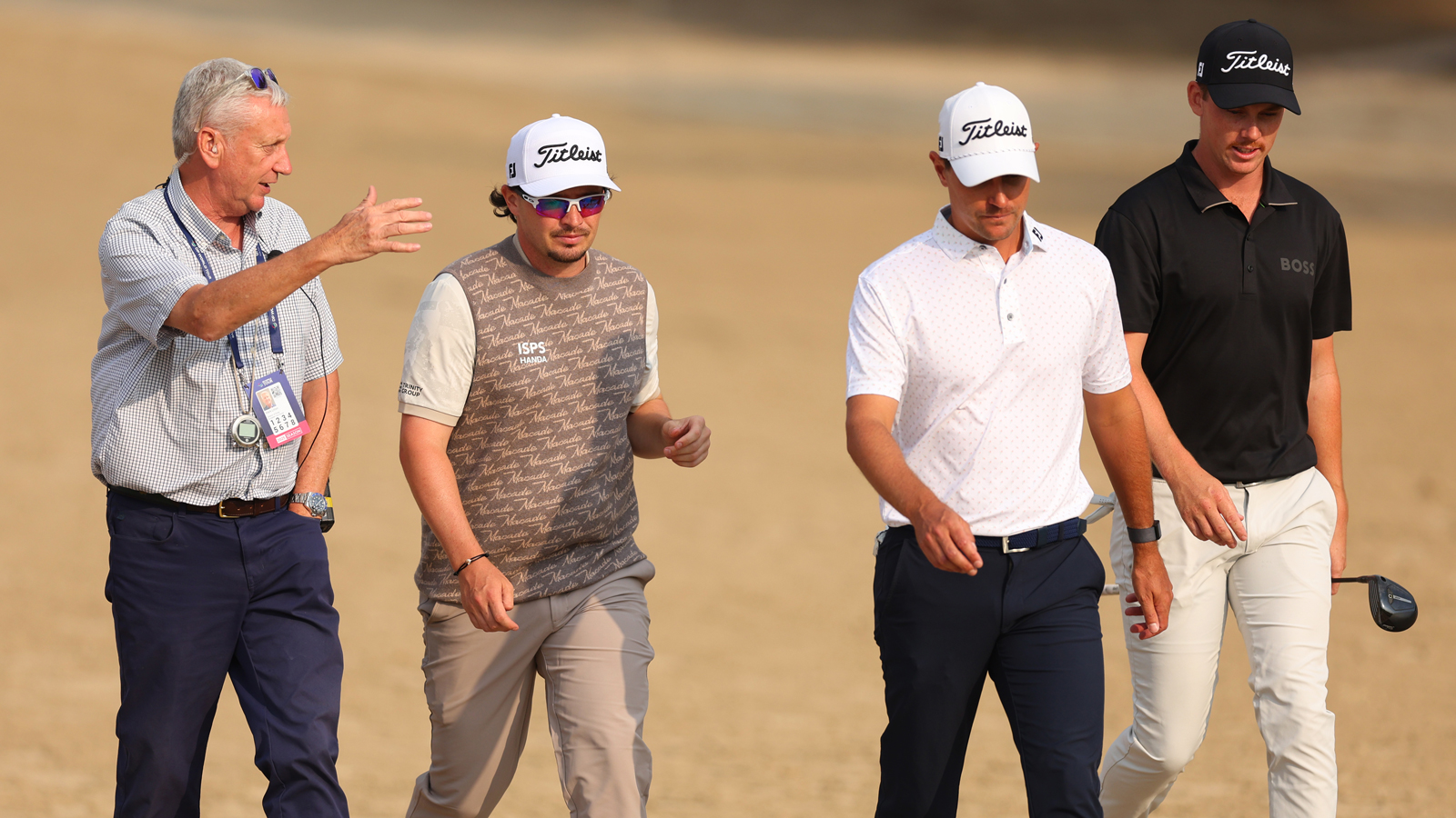 A rules official speaks to three golfers