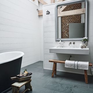 neutral bathroom with wooden bench and mirror