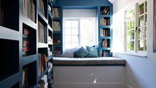 A bedroom with a nook seating area and book shelves