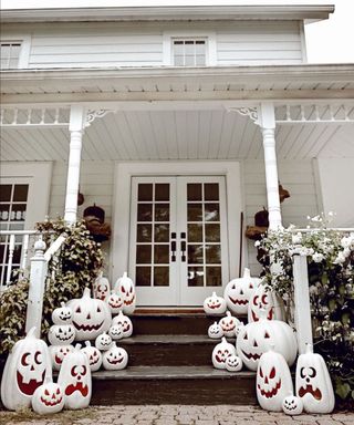 White 1800s farmhouse with assortment of carved and painted white pumpkins
