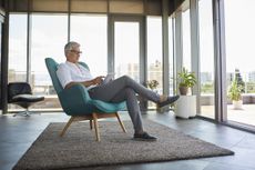 Mature man sitting in armchair at home using tablet