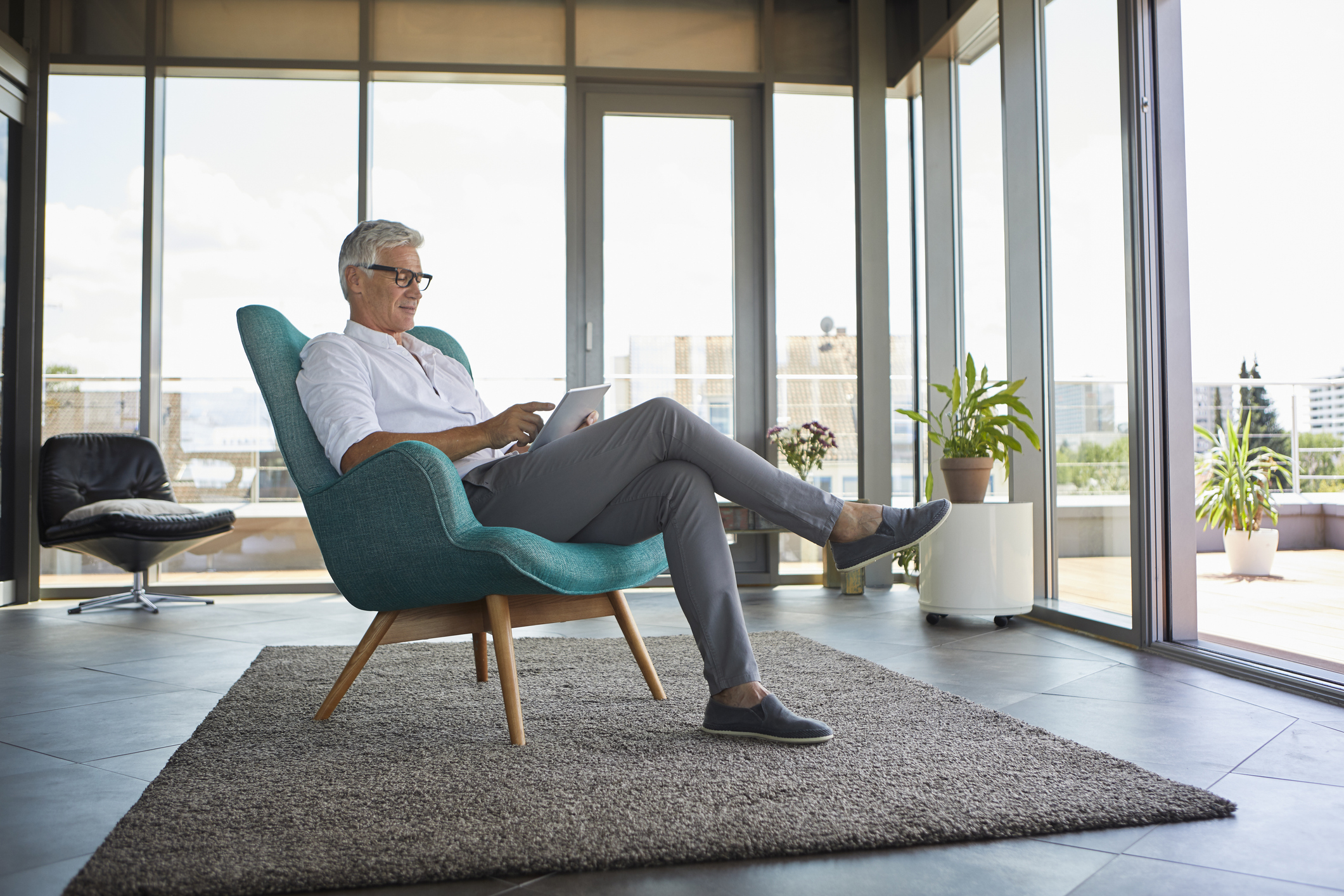 Mature man sitting in armchair at home using tablet