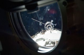 The Progress M-19M (51P) Russian cargo craft is seen through a window arriving at the International Space Station in April 2013. It departed on June 11 packed with trash, including the station's first treadmill, destined to be destroyed during re-entry into the Earth's atmosphere.