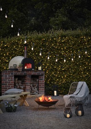 outdoor living area at night with festoon lights and a fire pit