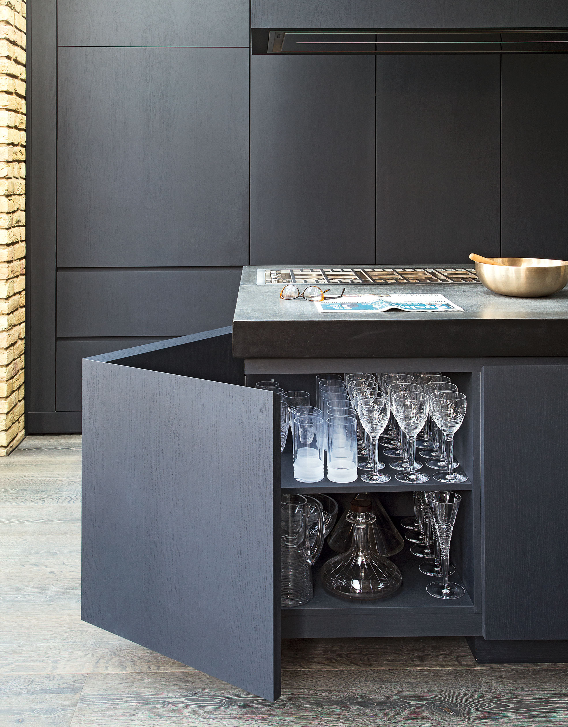 Kitchen island ideas with a corner opening cabinet in a sleek dark gray room.