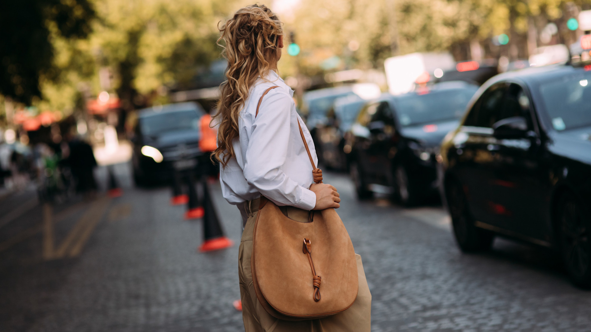 Blonde fashion week attendee looking away carrying a suede bag