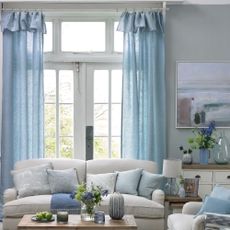 A living room with high ceilings and window covered by long blue curtains