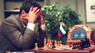 Garry Kasparov holds his head in his hands while sitting at a chessboard