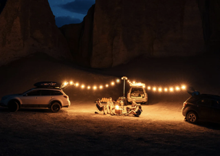 MPOWERD Luci solar lights set up between two cars in a desolate camping site
