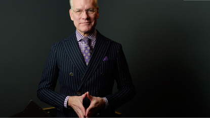 Man neatly dressed in a pinstripe suit and purple check shirt with purple tie