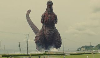 Shin Godzilla the monster towers over land, walking out of the water