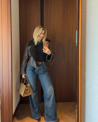 Woman wearing leather jacket, wide leg jeans and The Row Margaux bag