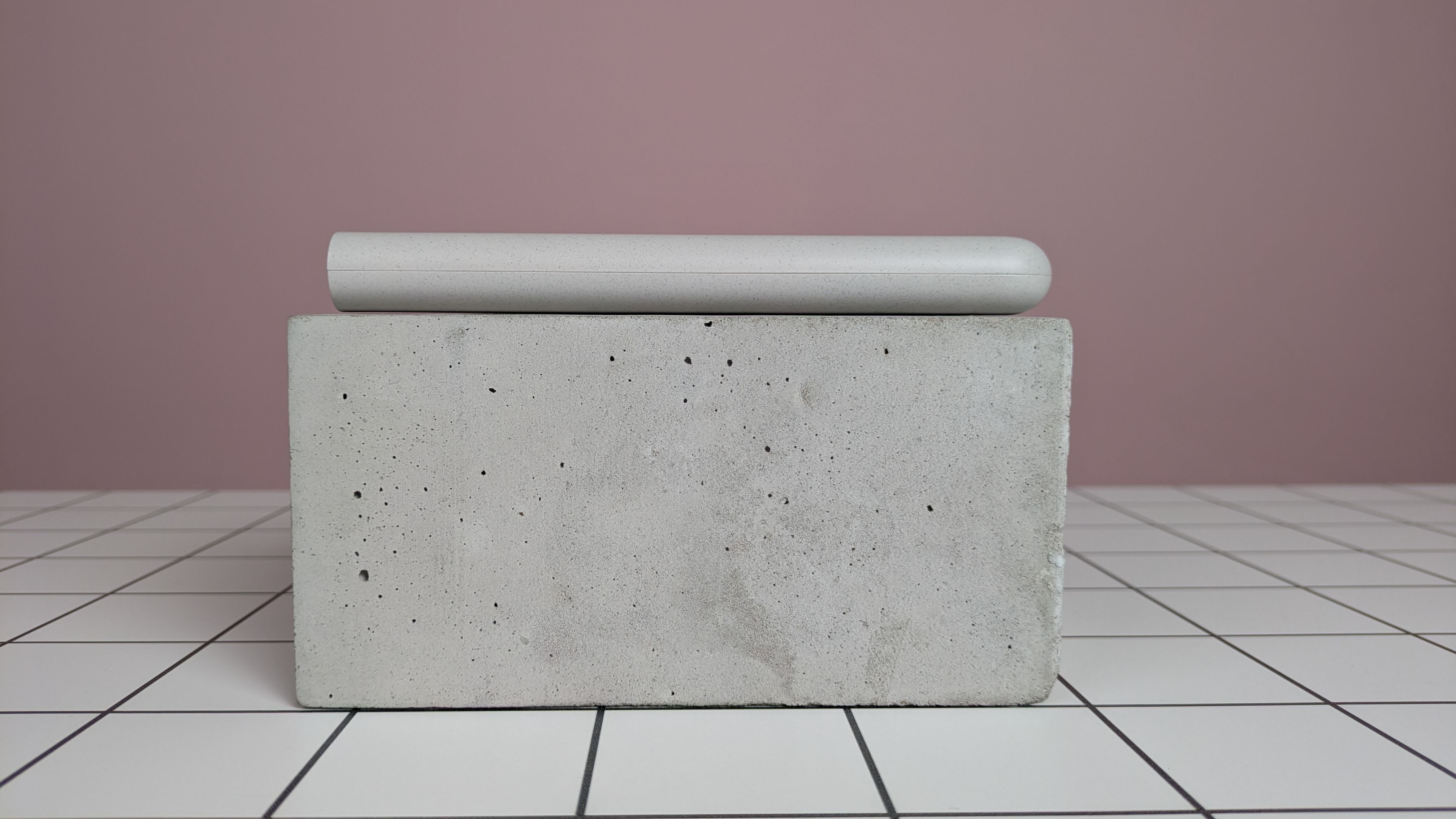 Samsung 25W 10,000mAh Wireless Battery Pack leaning on plinth, on desk with pink background