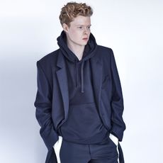 Kai Alexander wearing a navy hoodie styled with a matching blazer and pants. 