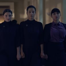 three girls including lucy halliday chase infiniti and rowan blanchard wear dark purple dresses walking down a hall in the testaments season 1 finale