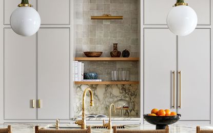 light grey kitchen cabinets with marble worktop, wooden shelves and brass handles