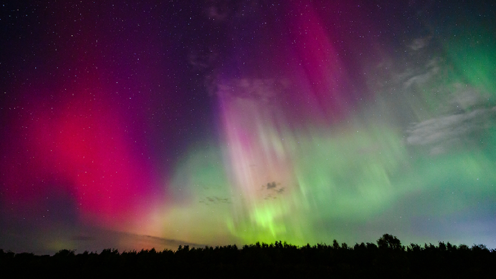 A photo of vibrant multicolor auroras streaking across the night sky