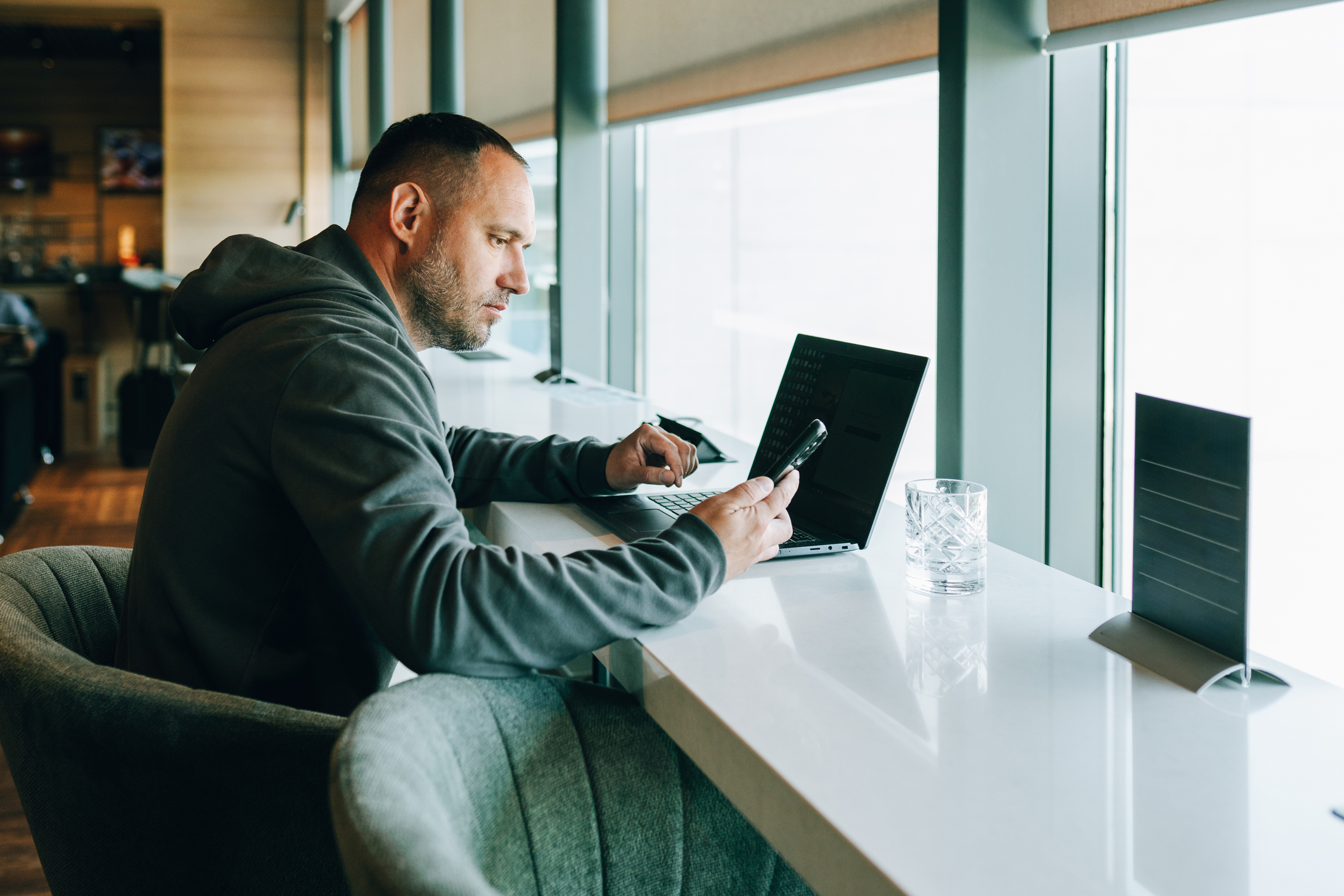 Man working on laptop and smartphone in airport lounge