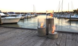 Trio of fire pits on a wood jetty with boats in background
